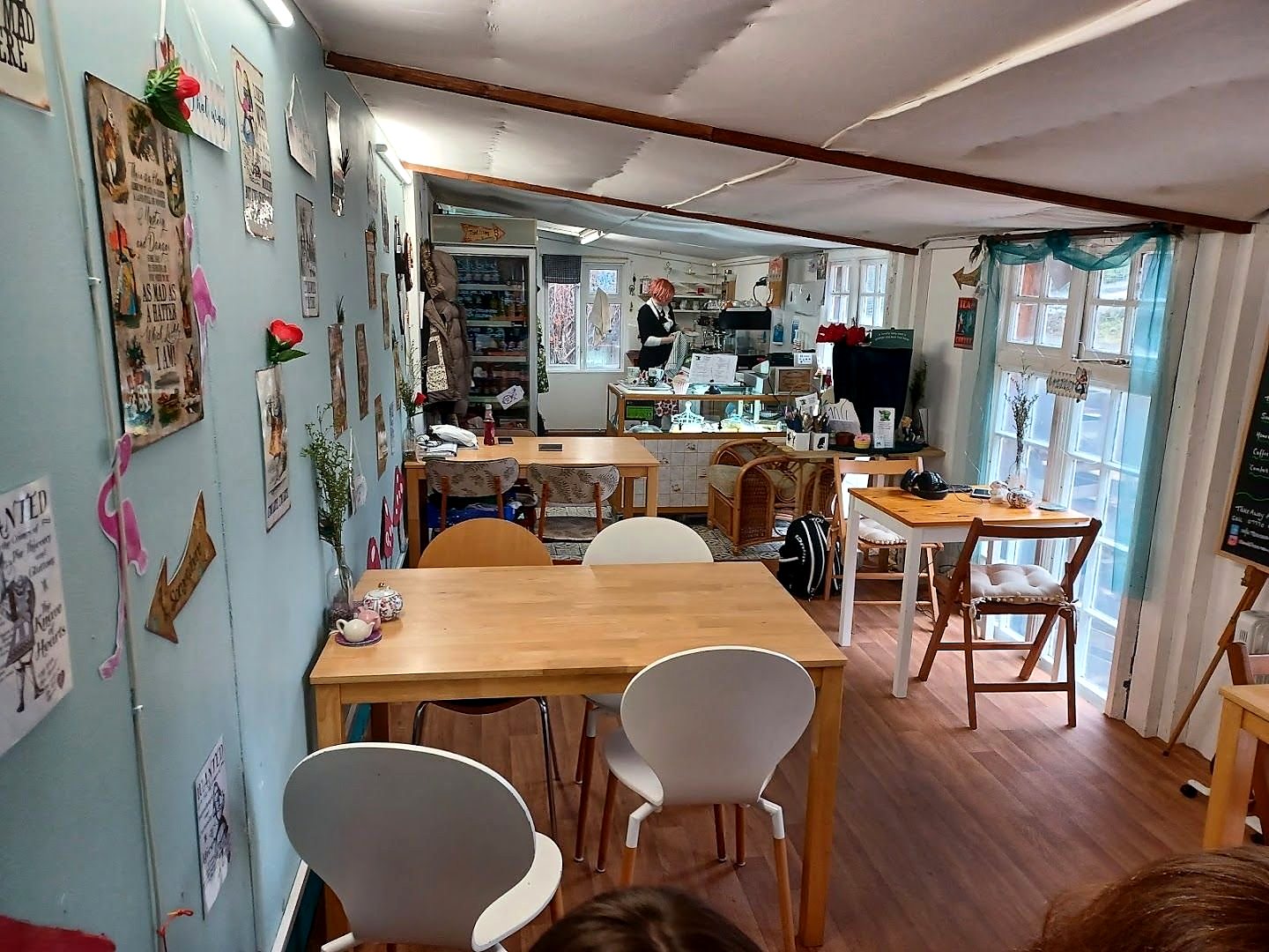 Inside the tea room: pale blue walls hung with pictures, wooden tables, white chairs and tall windows